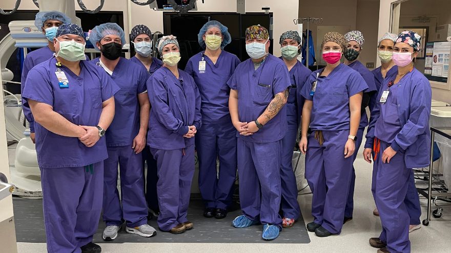 A team of clinical professionals in the Cardiac Catheterization Lab at Renown Health pose for a group photo.