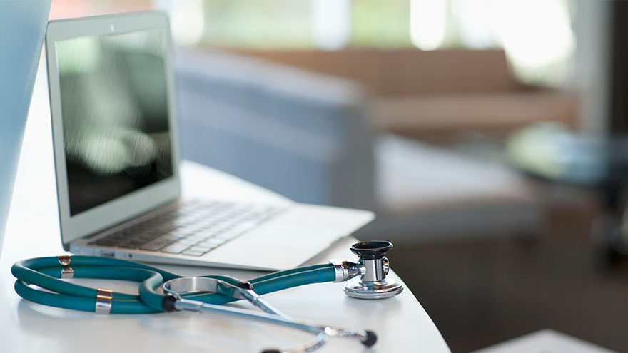 Laptop and stethoscope on desk