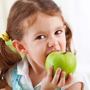 A small girl eating a green apple
